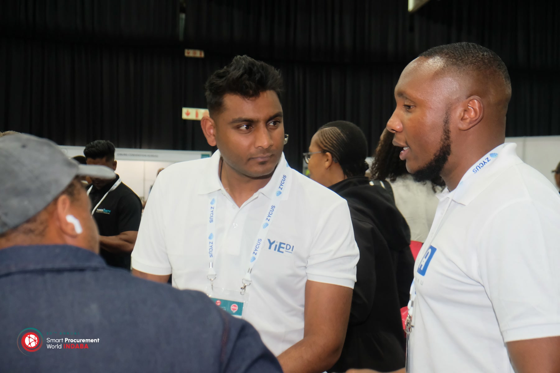Gift Lubele speaking with a Rinku and YIEDI colleague at Smart Procurement World Indaba. Photograph.