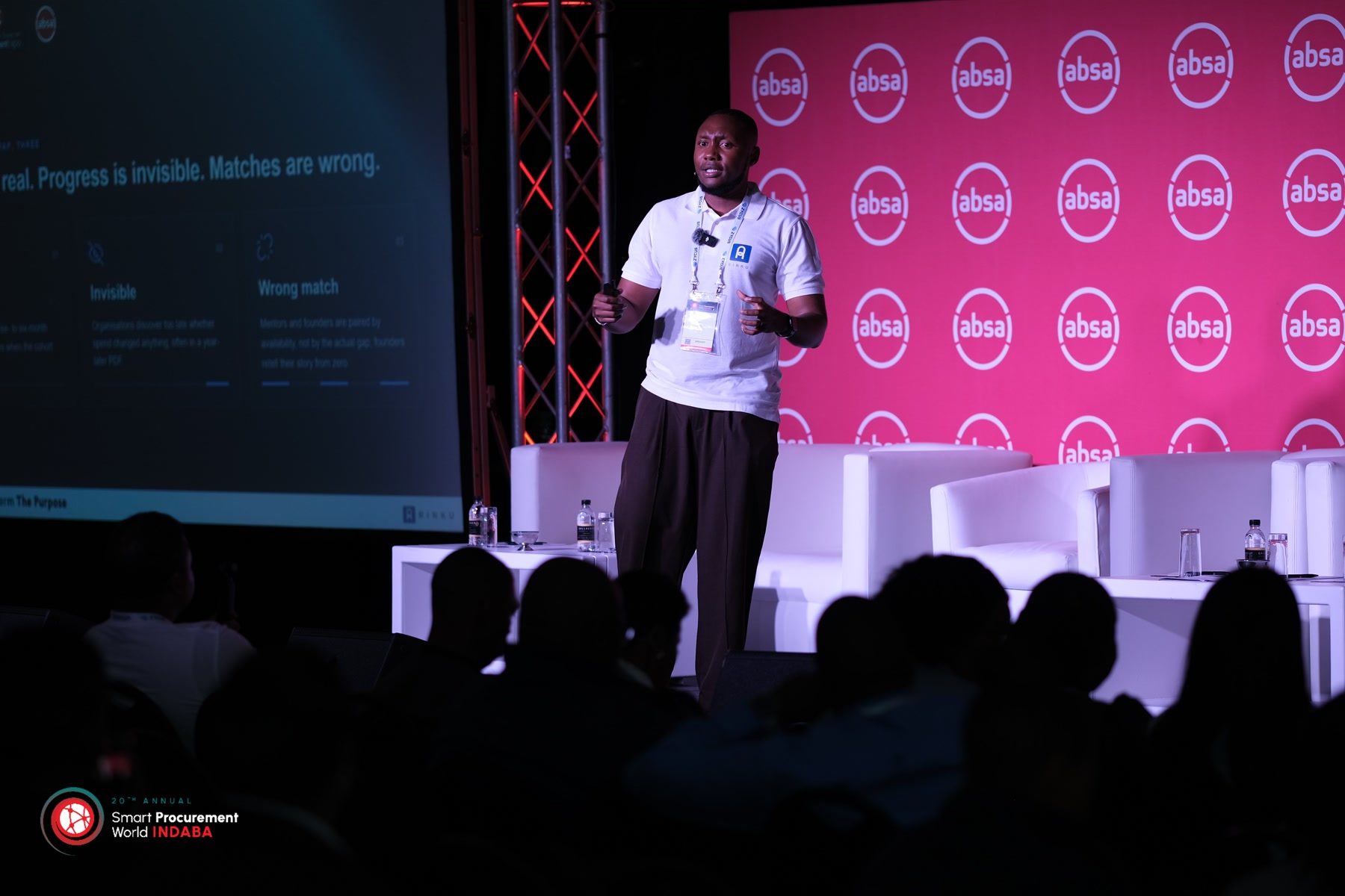 Gift Lubele on stage at the 20th Annual Smart Procurement World Indaba, Absa backdrop and audience in silhouette. Photograph.